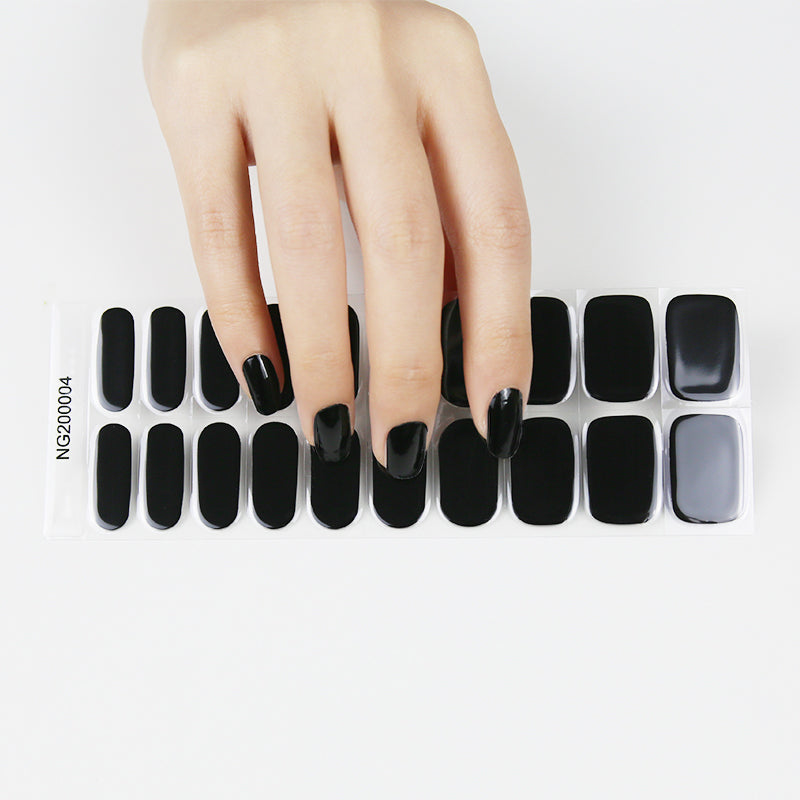 Hand with black nail wraps holding a package of 20 black nail wraps on a white background