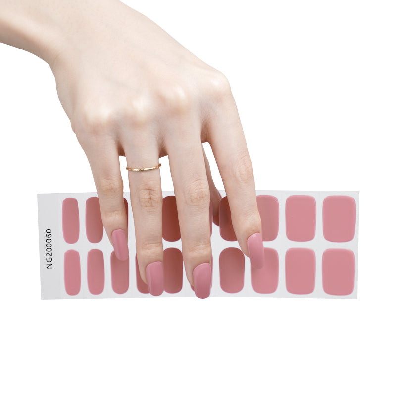 Hand holding a strip of pink nail stickers with a white background