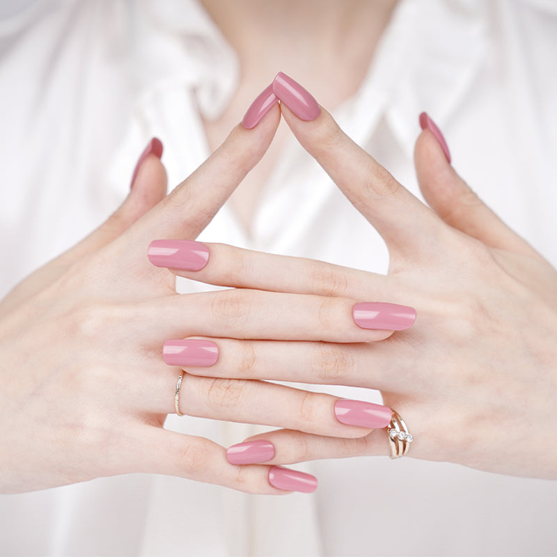 Close-up of hands with pink nail polish wraps on a white background