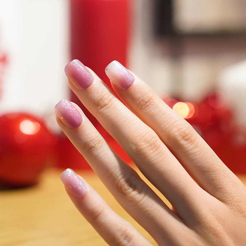 Close-up of a hand wearing sheer mauve and white gradient semi-cured gel nail polish strips.