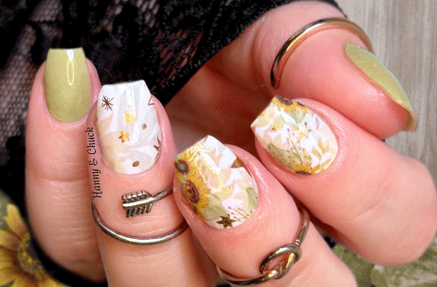Close-up of hands with sunflower nail nail wraps with green accents.