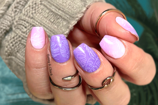 Hand with purple and pink nail wraps design wearing multiple rings