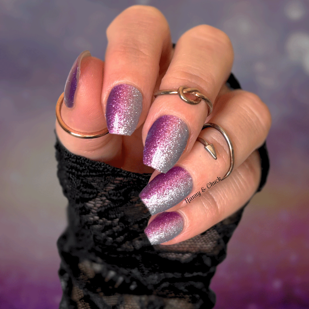 Hand with glittery purple and silver nail polish wraps against a blurred purple background