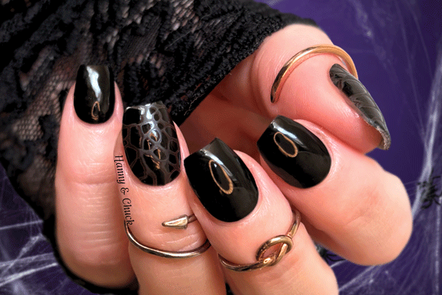 Close-up of a hand with black and snake print nail polish wraps.