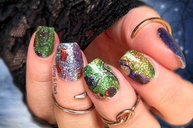 Close-up of a hand with colorful glittery nail polish and multiple rings.