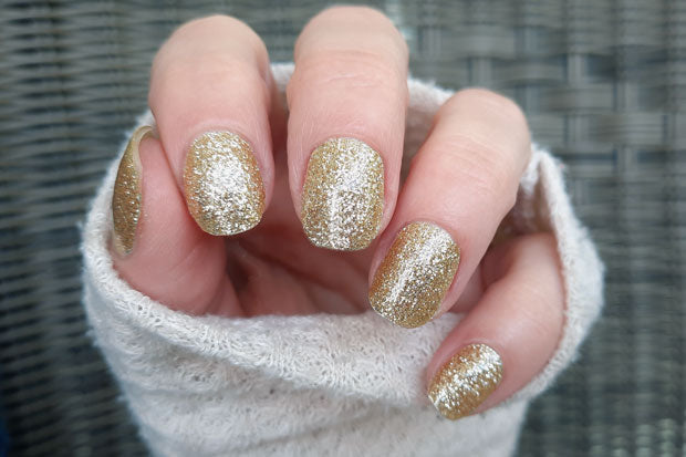 Image of glittery gold nail wrap manicure on short nails.