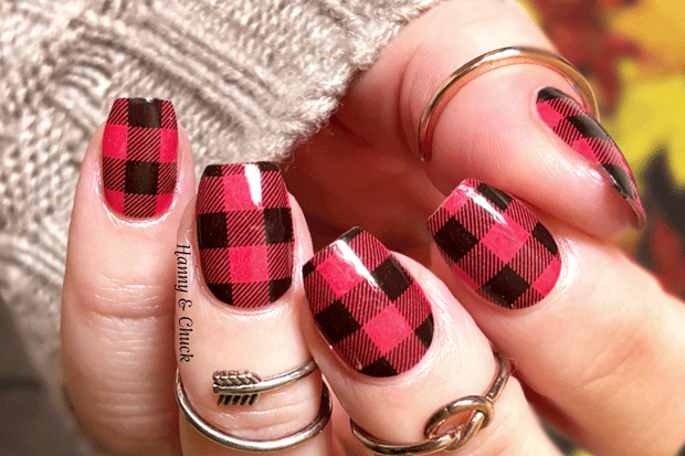 Nails with red and black plaid nail wrap design on a blurred background
