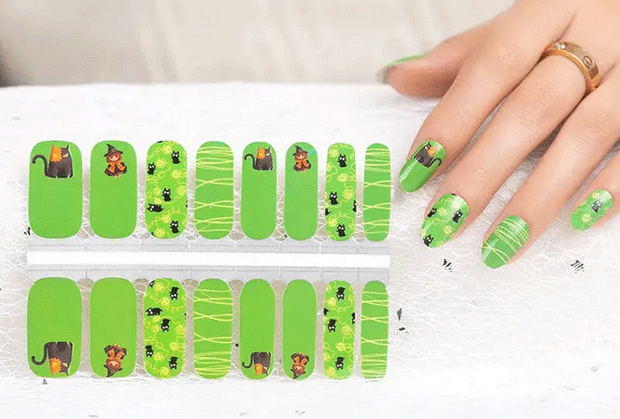 Green nail wraps with animal designs on a tray, next to a hand with green nail wraps applied.