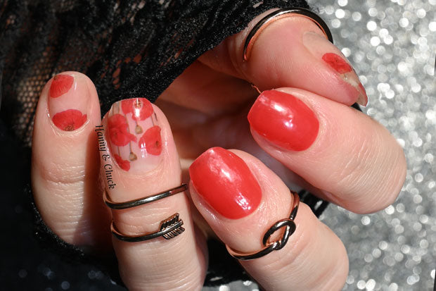 A hand wearing poppy themed nail polish wraps