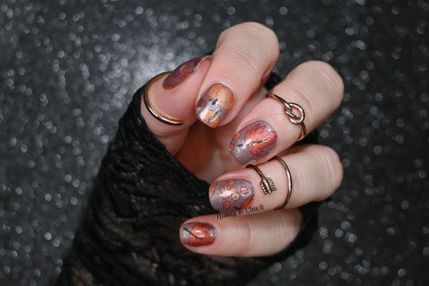 A person's hand with nail wraps featuring a multicolor autumnal design, showcasing the nail art kit effect.