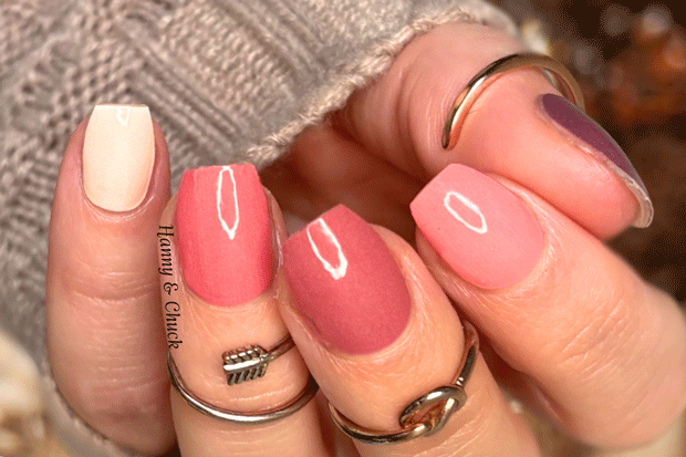 Close-up of a hand with pink ombre nail polish wraps and multiple rings.