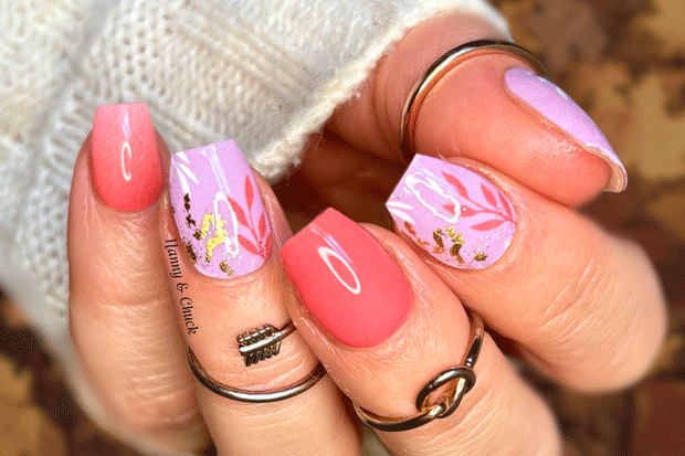 Close-up of a hand with pink and purple floral nail wraps on a blurred background