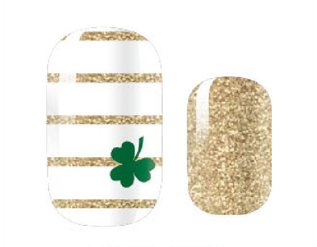 This image shows two St. Patrick's Day-themed nail art strips. The first strip features alternating horizontal lines of white and gold glitter with a green shamrock in the bottom corner. The second strip is a solid gold glitter design.