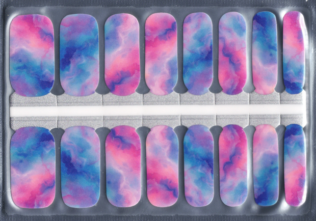 Dreamland nail wraps are displayed in a flat lay, showcasing a soft blend of pastel blue, pink, and purple hues across 16 nail strips. The watercolor-like design creates a dreamy, ethereal effect reminiscent of a sunset or nebula. 