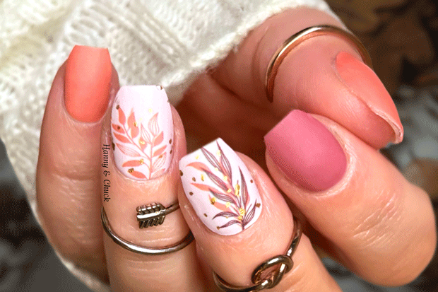 Close-up of a hand with pink and white floral nail art on a blurred background
