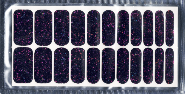 A rectangular white sheet displays 22 nail polish wraps, arranged in two rows of varying widths. The wraps are designed to adhere to fingernails, offering a pre-made manicure look. Each nail polish wrap features a dark, almost black base colour speckled with a vibrant mix of purple, teal and light blue glitter particles, adding depth to the cosmic effect. The wraps vary slightly in width, suggesting they are designed for different nail sizes.