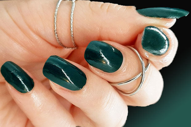 Hand wearing dark green nail wraps